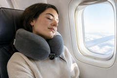 Person sleeping comfortably on an airplane wearing a memory foam travel neck pillow